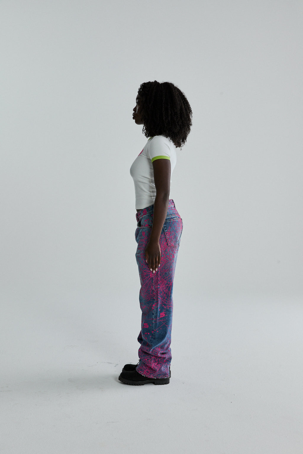 Woman in white cropped SEX BABY TEE with green trim, paired with blue and pink graphic print jeans.