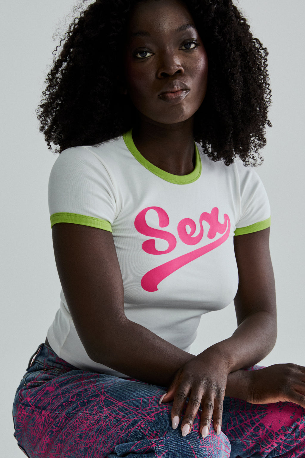 White cropped fitted cotton/spandex tee with "Sex" graphic in pink, green ribbed trim.