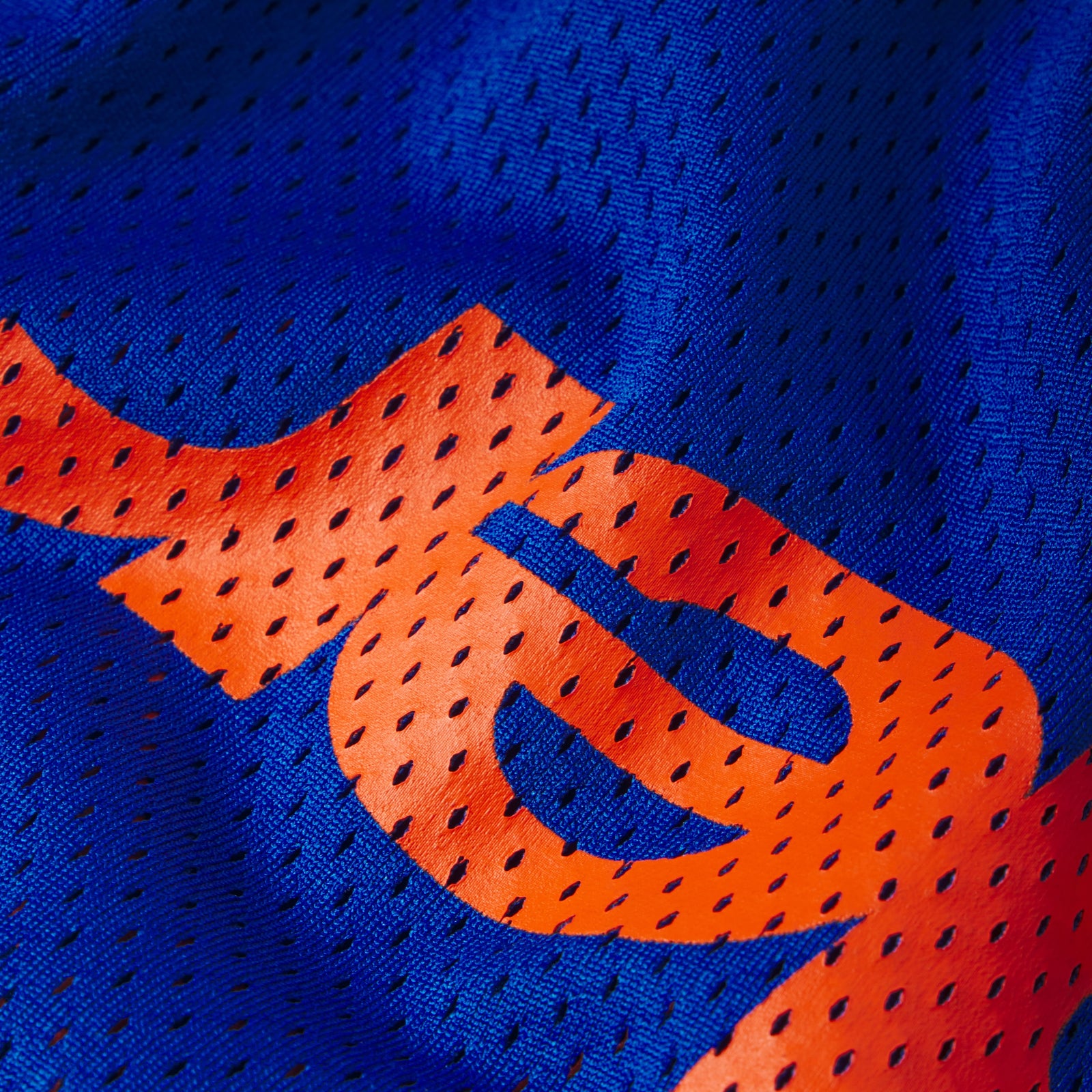 Blue breathable mesh fabric featuring a bold orange graphic print design.