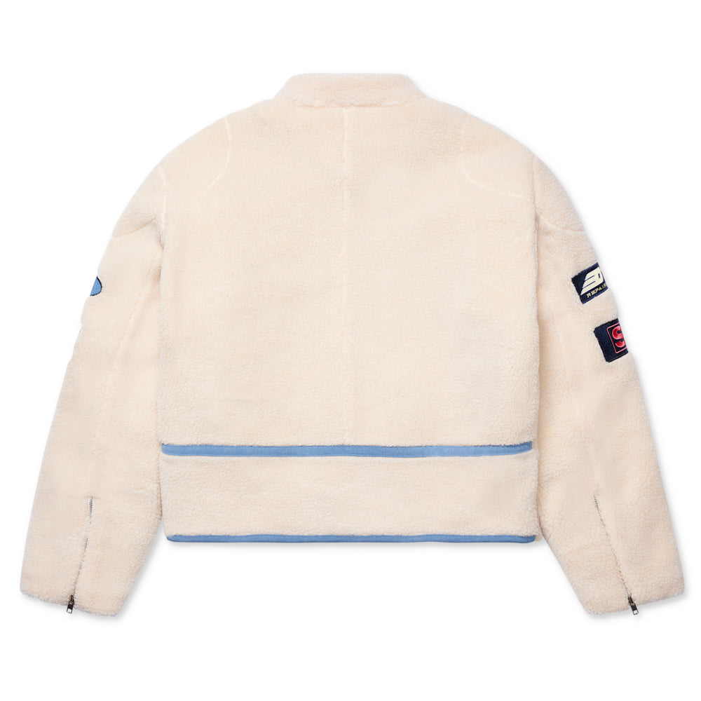 Cream sherpa moto jacket with blue leather trim, SP5DER patches on sleeves, and zippered cuffs.