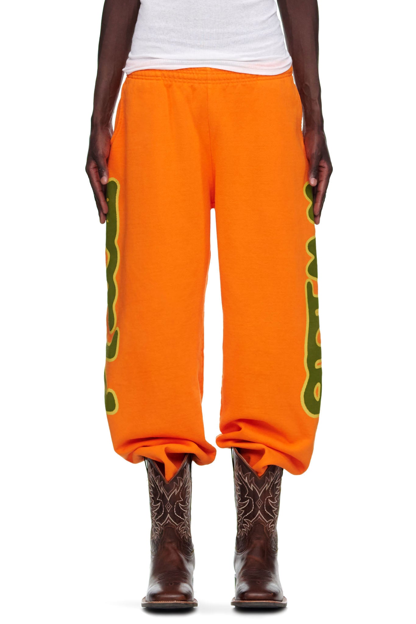Orange BELUGA SWEATPANT with green 'Worldwide' puff print down both legs, worn by a male model.