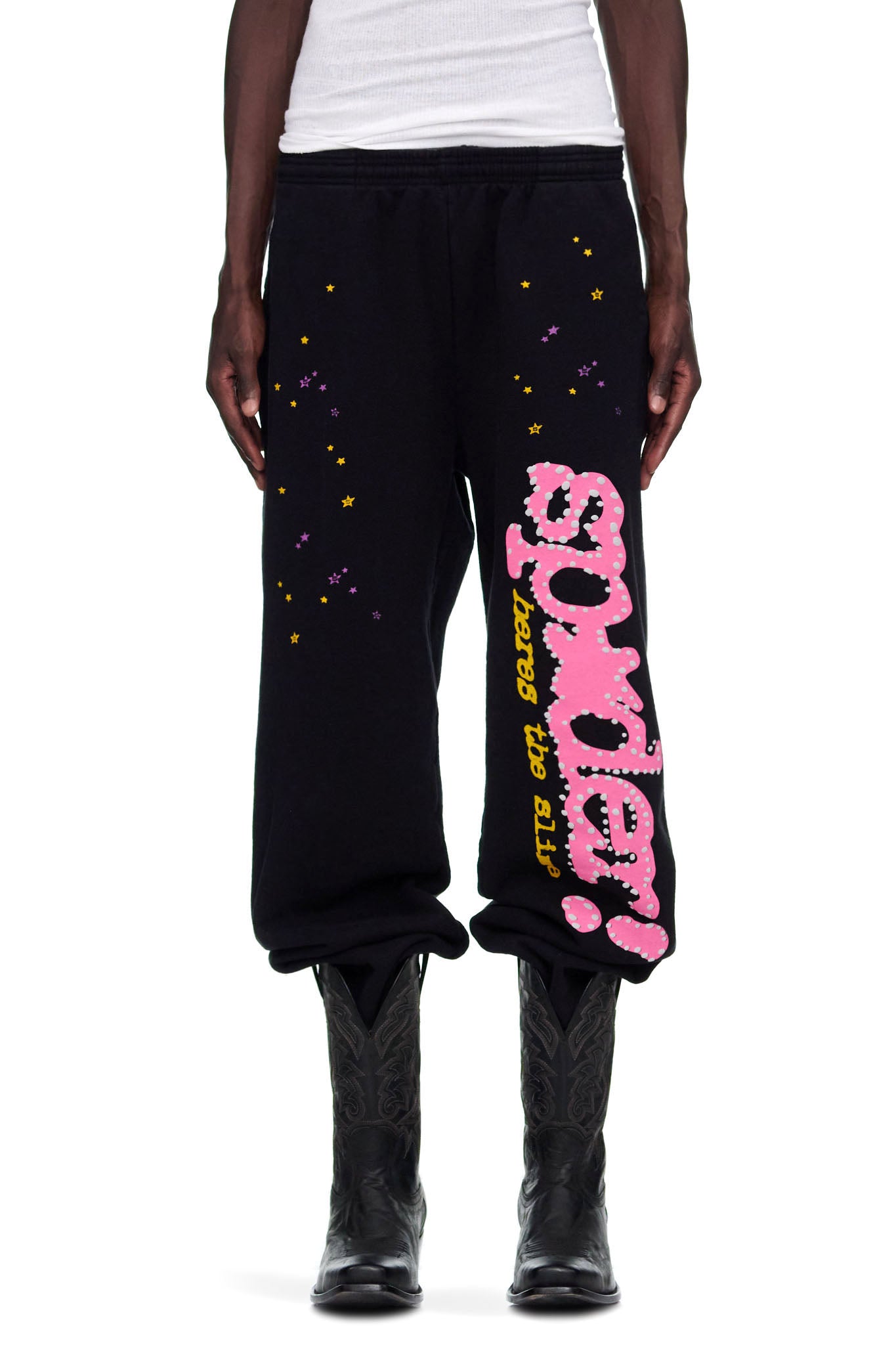 Black 23oz fleece sweatpants with pink puff print "SP5DER" motif, yellow text, and scattered purple and yellow stars.