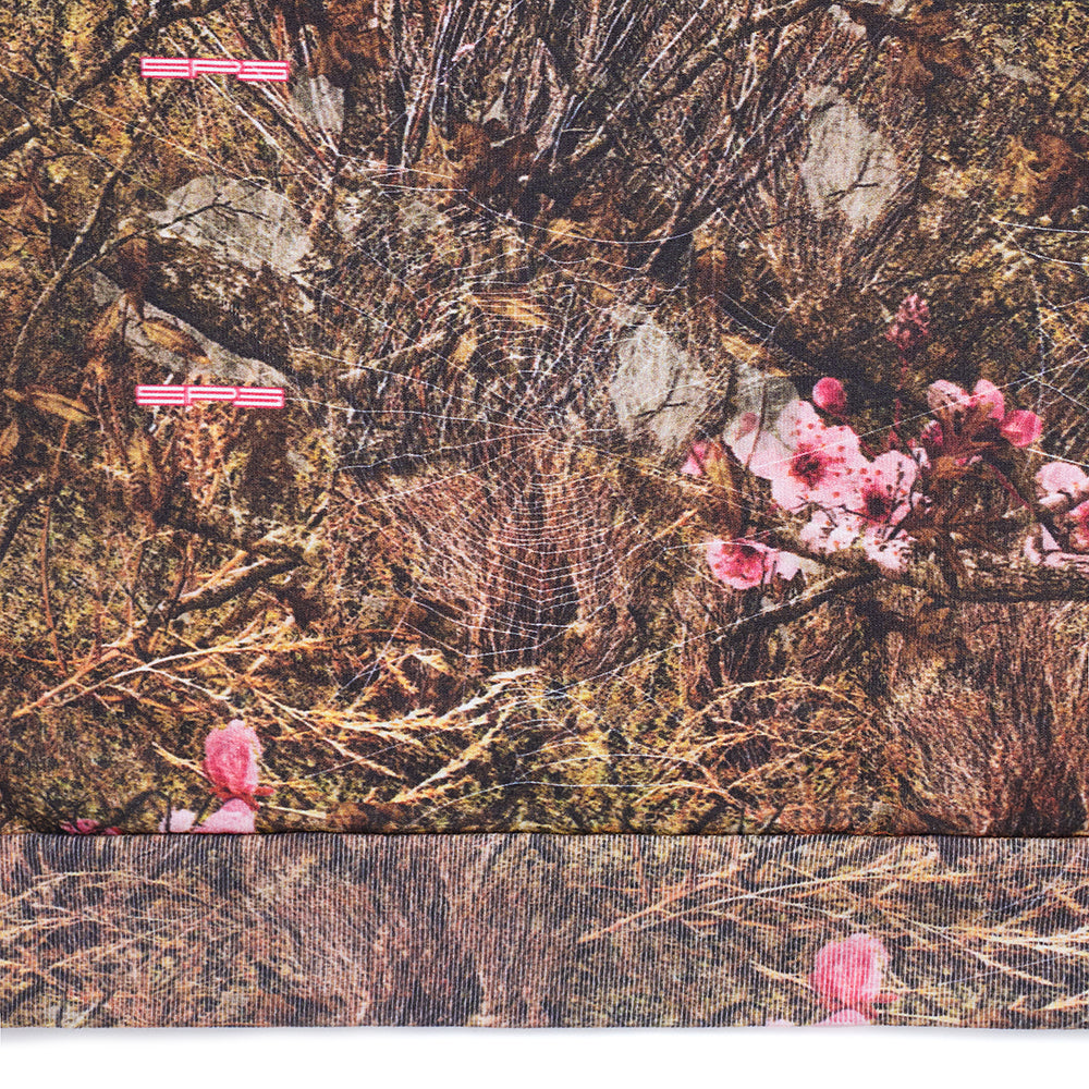 Real Tree OG Web Hoodie: Brown camouflage 23oz fleece with pink flowers, white spiderweb, and red stripes.