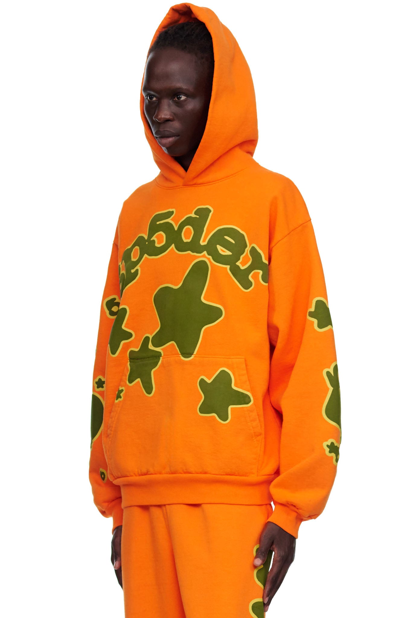 Orange BELUGA HOODIE with green 'SP5DER' puff print and star designs, worn by a male model.