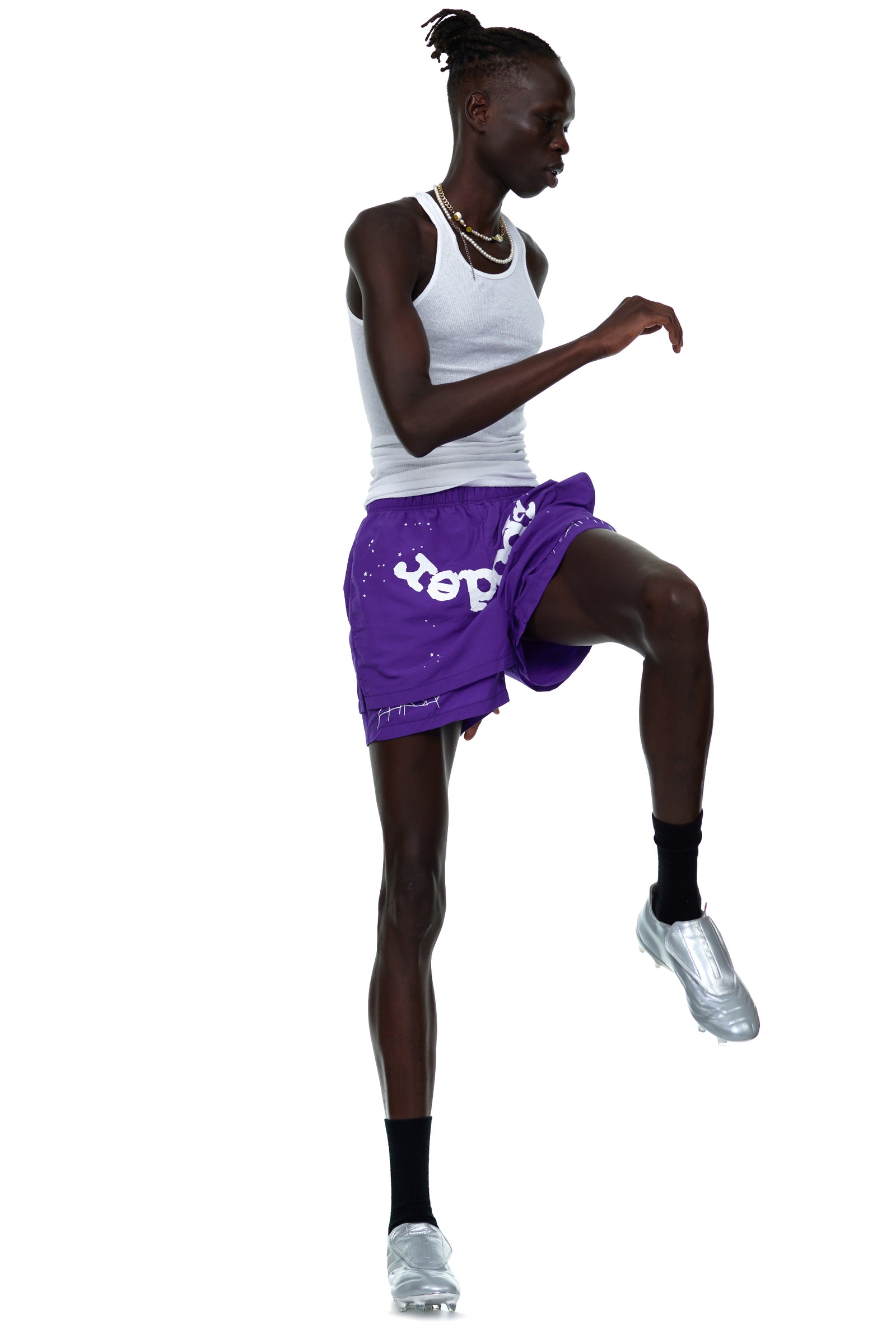 Model wearing purple GRAPE LOGO SHORT with white OG SP5DER text and web print, white tank top, and silver shoes.