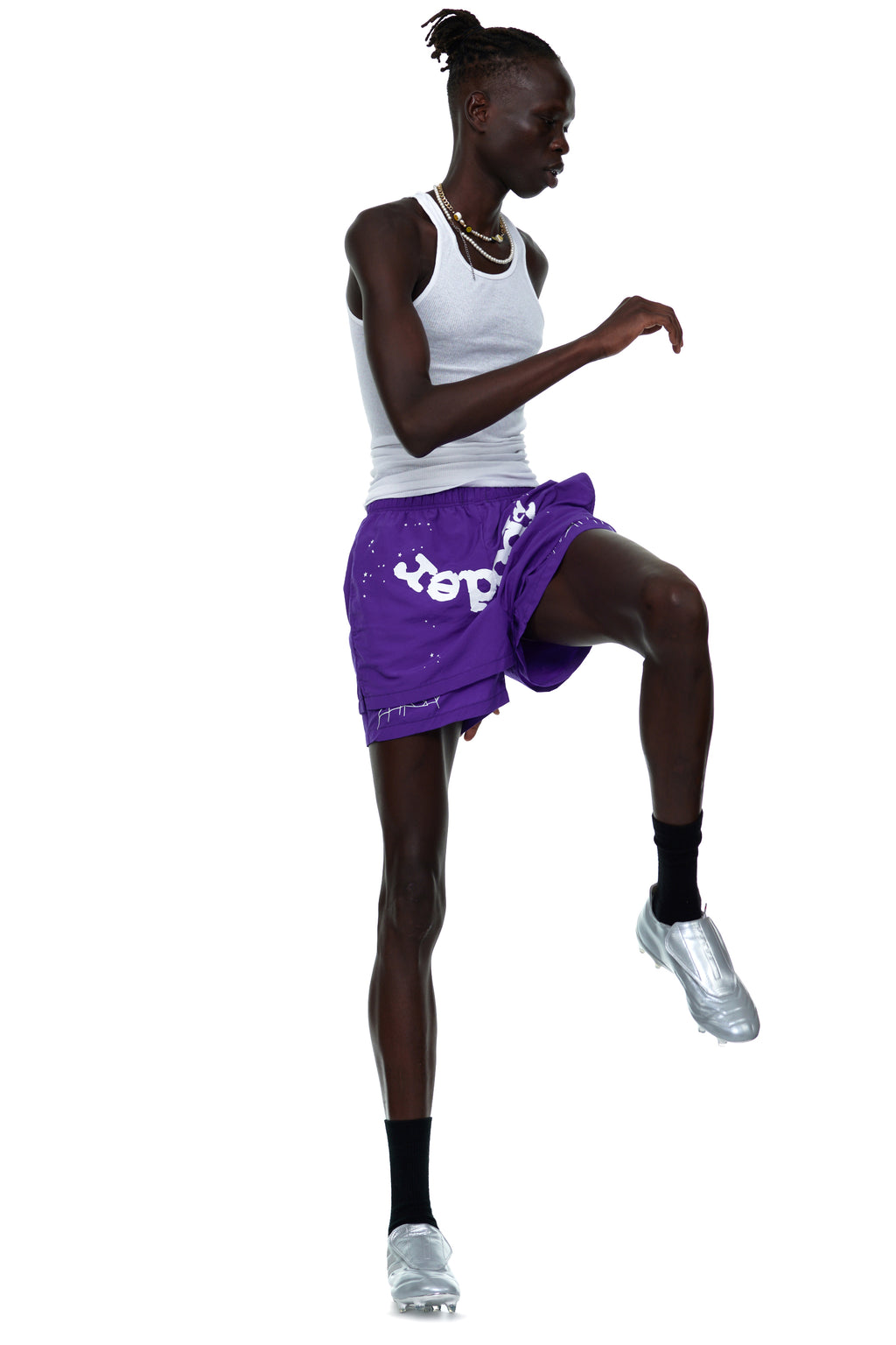 Model wearing purple GRAPE LOGO SHORT with white OG SP5DER text and web print, white tank top, and silver shoes.