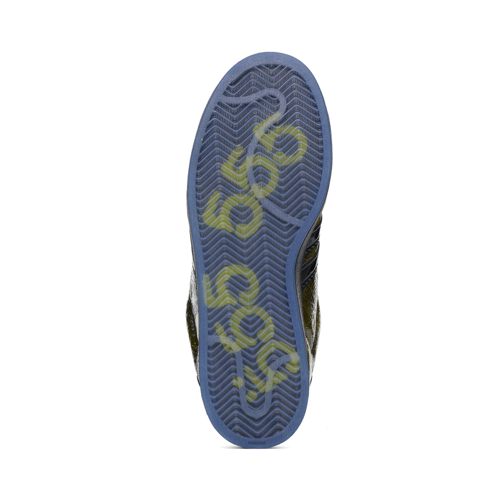 SP5DER x ADIDAS SUPERSTAR sneaker, showing its translucent blue rubber outsole with yellow graphic detailing.