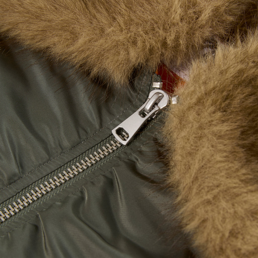Close-up of an olive green nylon flight jacket with a silver zipper and brown faux fur collar.