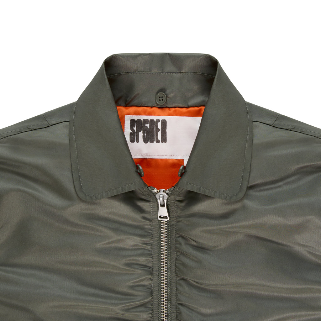 Olive green nylon bomber jacket with orange lining, silver zipper, and SP5DER neck label.