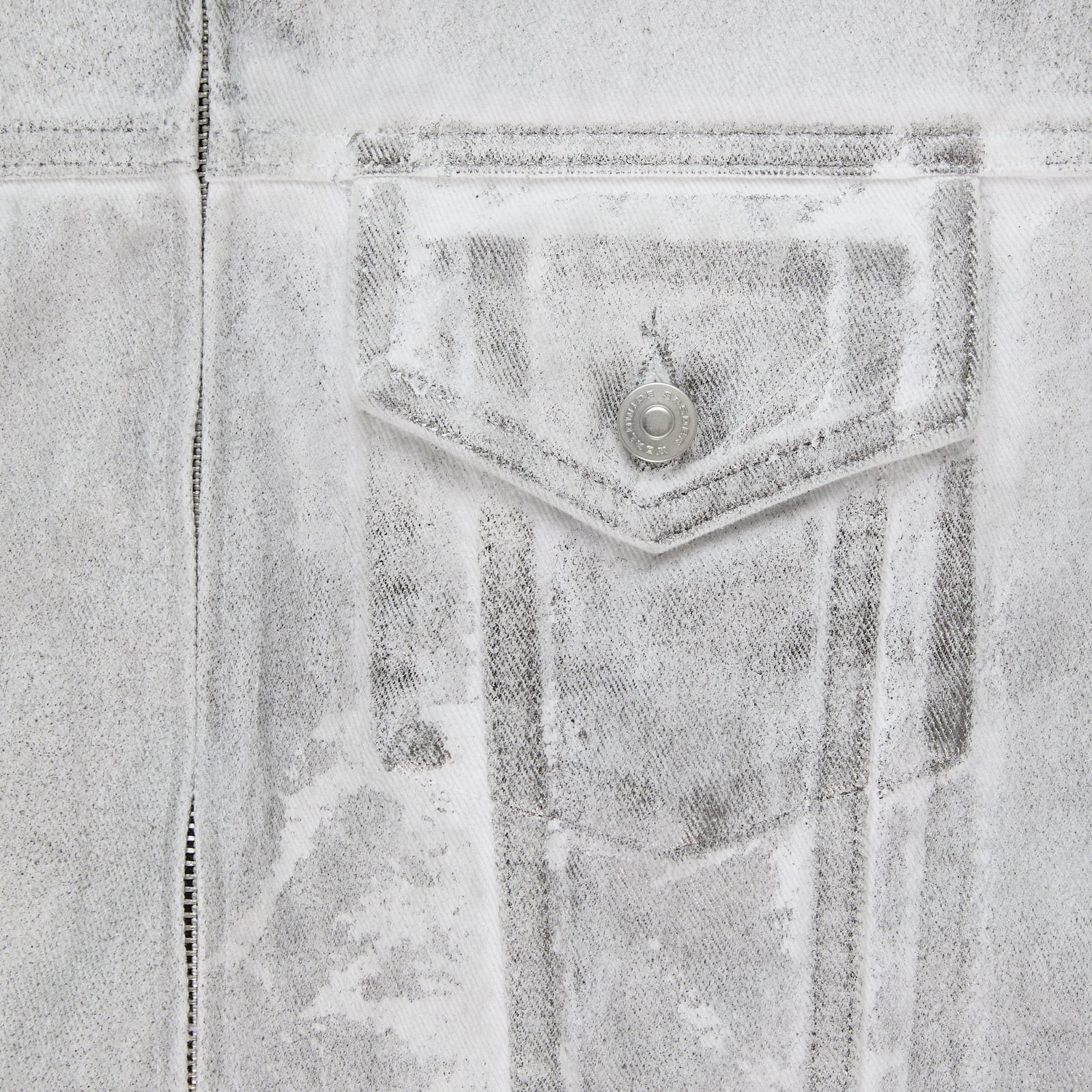Close-up of a PLATINUM TRUCKER JACKET, showing the spray-effect denim, contrast seams, and chest pocket with snap button.