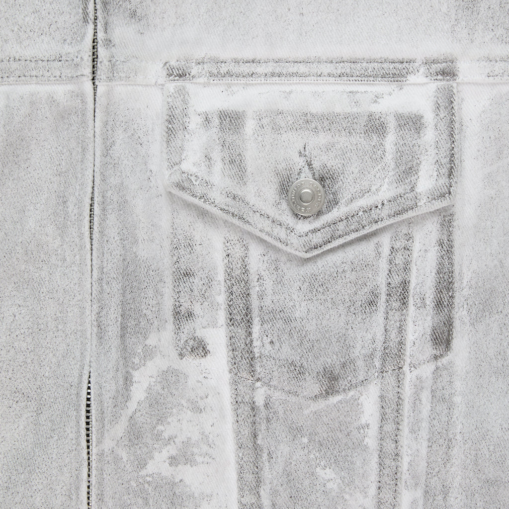 Close-up of a PLATINUM TRUCKER JACKET, showing the spray-effect denim, contrast seams, and chest pocket with snap button.