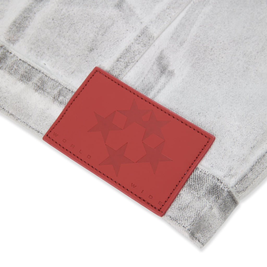 Close-up of a red leather patch with embossed stars and "WORLD WIDE" on a platinum spray-effect denim jacket.