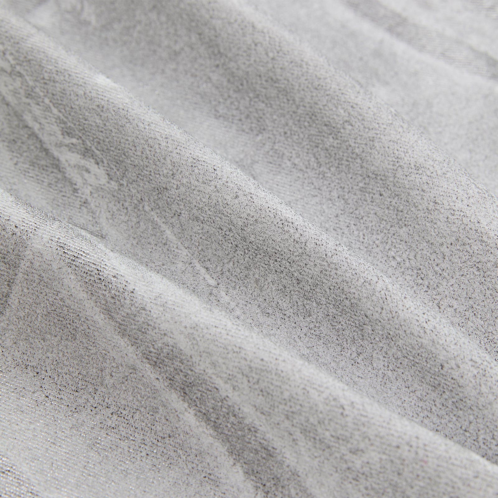 Close-up of platinum spray-effect denim fabric with subtle texture and soft folds.