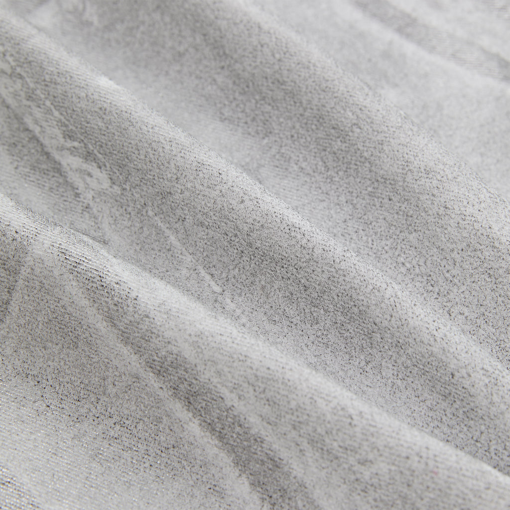 Close-up of platinum spray-effect denim fabric with subtle texture and soft folds.