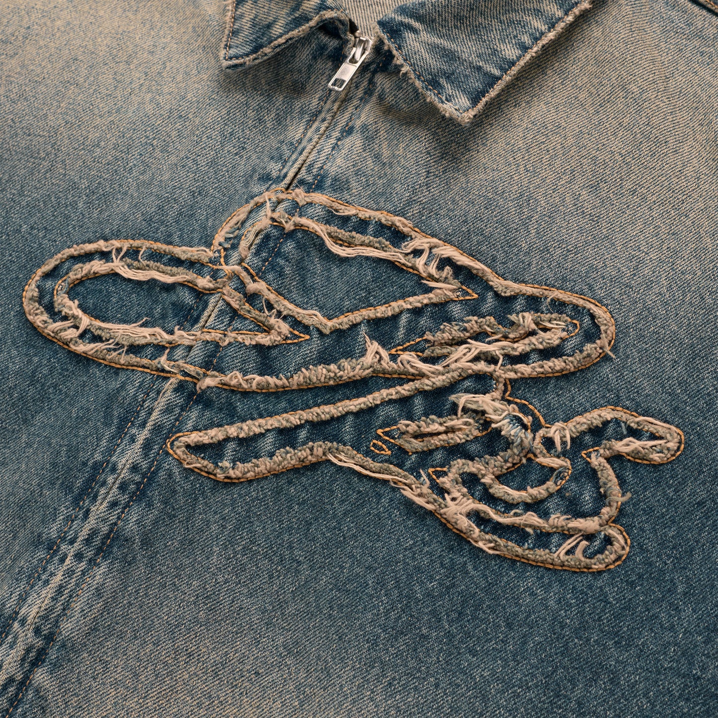 Washed blue denim work jacket with a unique, distressed script logo embroidery and silver zipper.