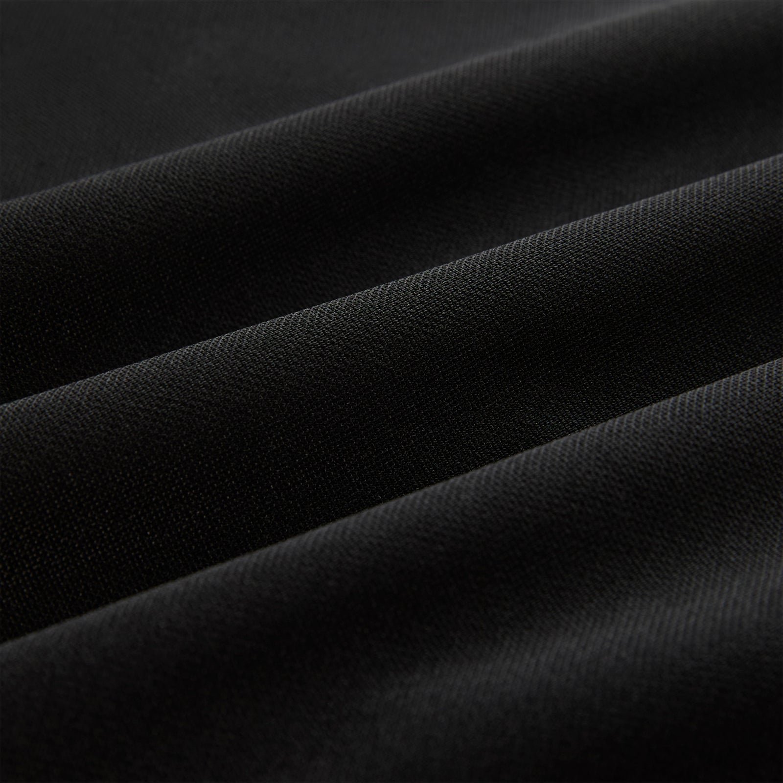 Close-up of black athletic polyester fabric with subtle texture and soft folds.