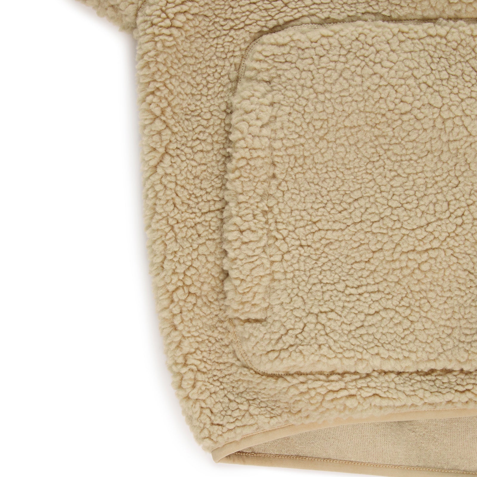 Close-up of a beige teddy sherpa fleece zip-up jacket with a welt pocket.