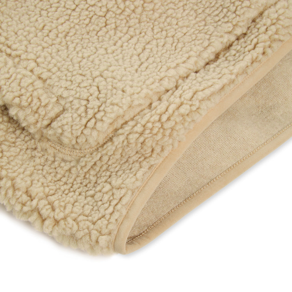Close-up of a beige teddy sherpa fleece fabric, showing its textured exterior and smooth inner lining.