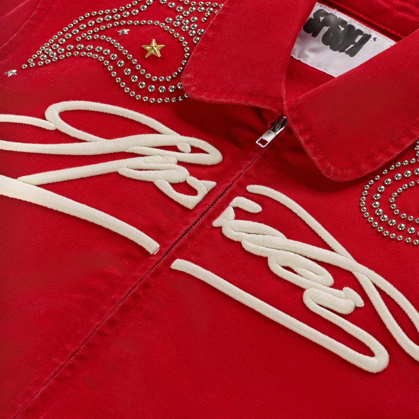 Red cotton canvas bomber jacket with white embroidered script, silver studs, and a gold star.