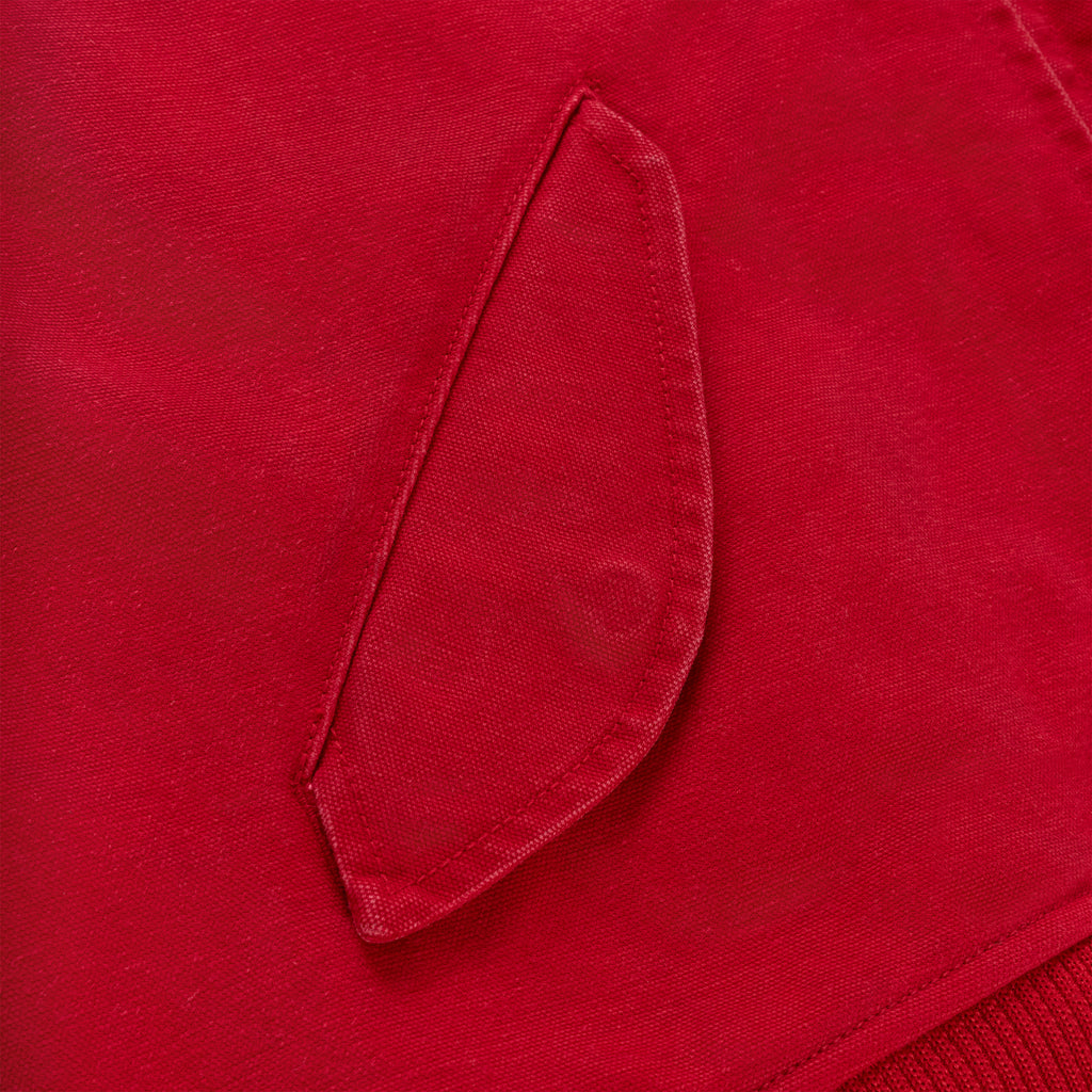 Close-up of a red cotton canvas bomber jacket with a flap pocket and ribbed hem.