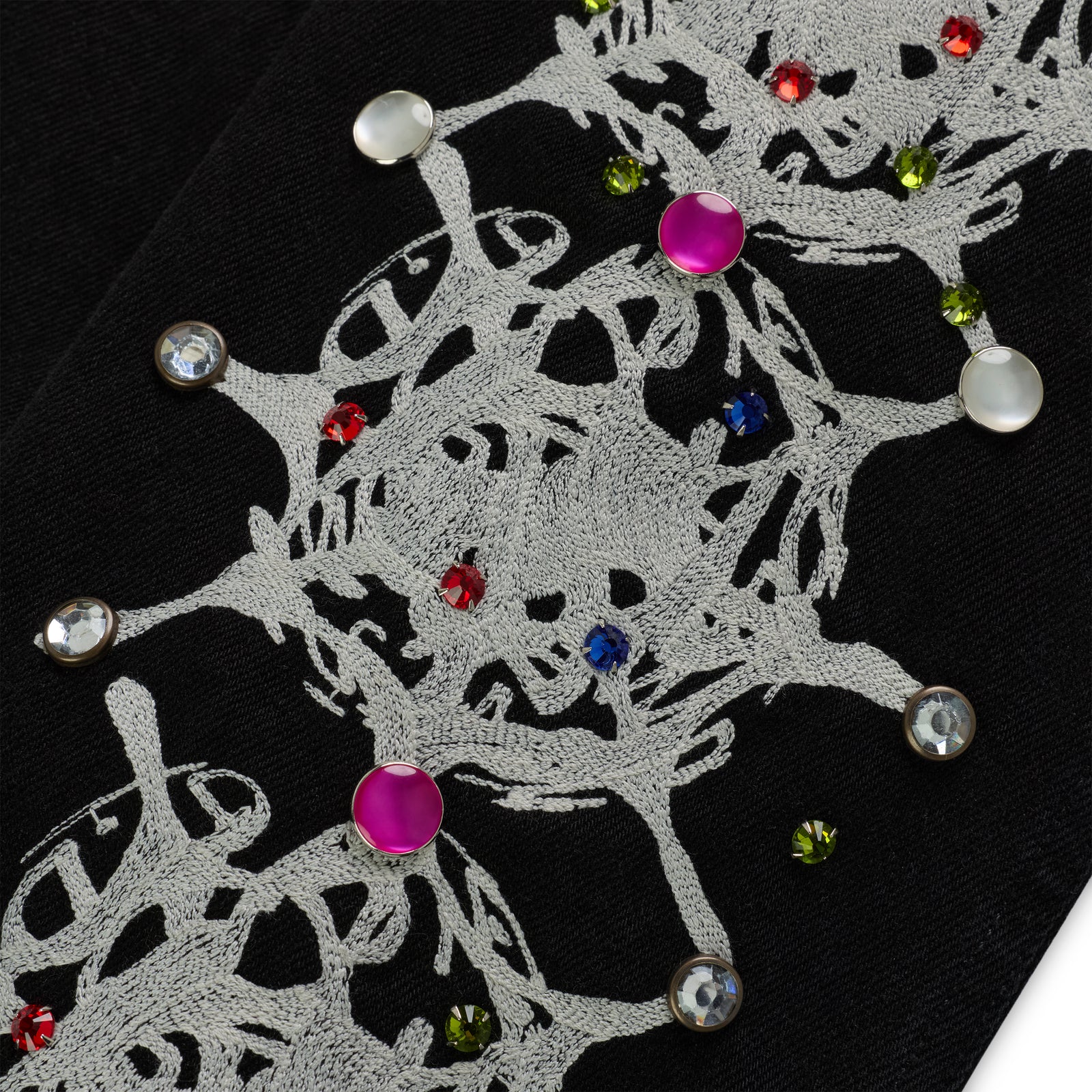 Close-up of black cotton canvas with white web print and colorful rhinestone embellishments.