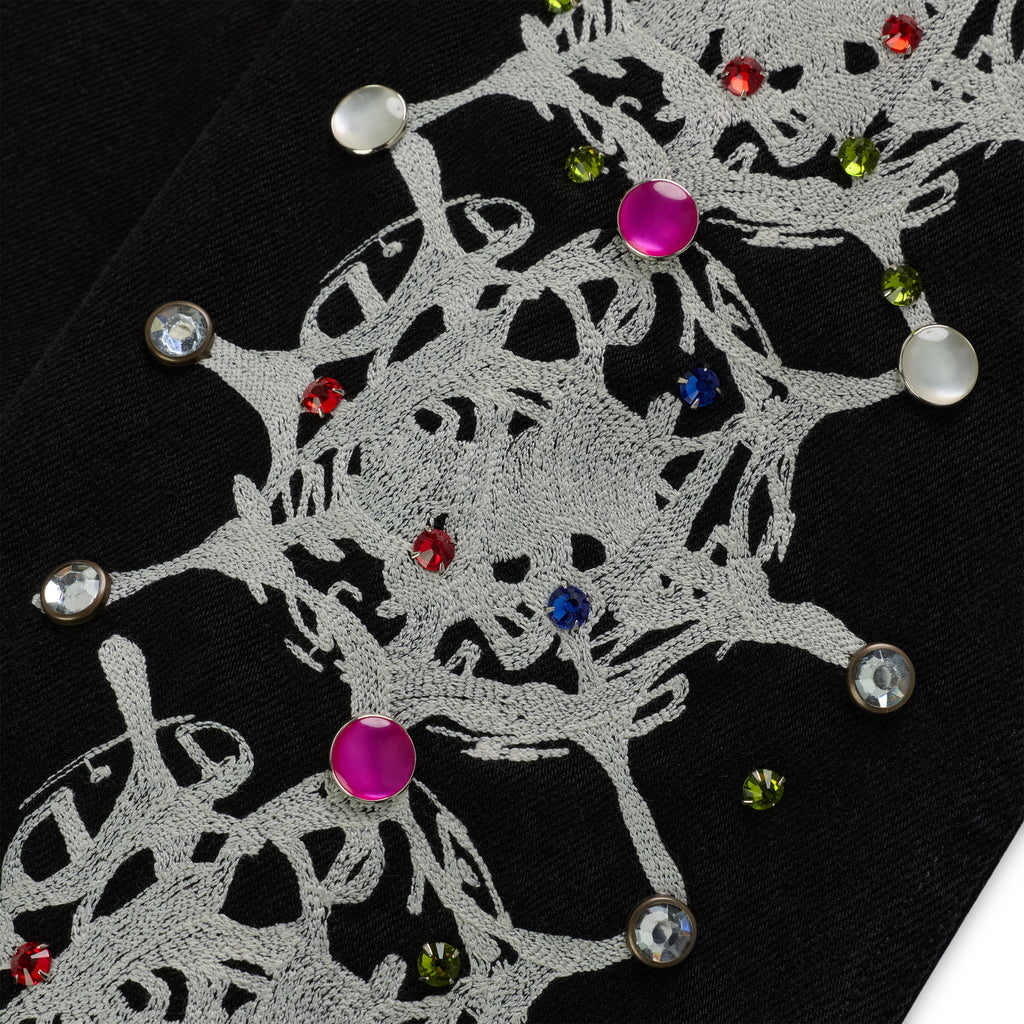Close-up of black cotton canvas with white web print and colorful rhinestone embellishments.