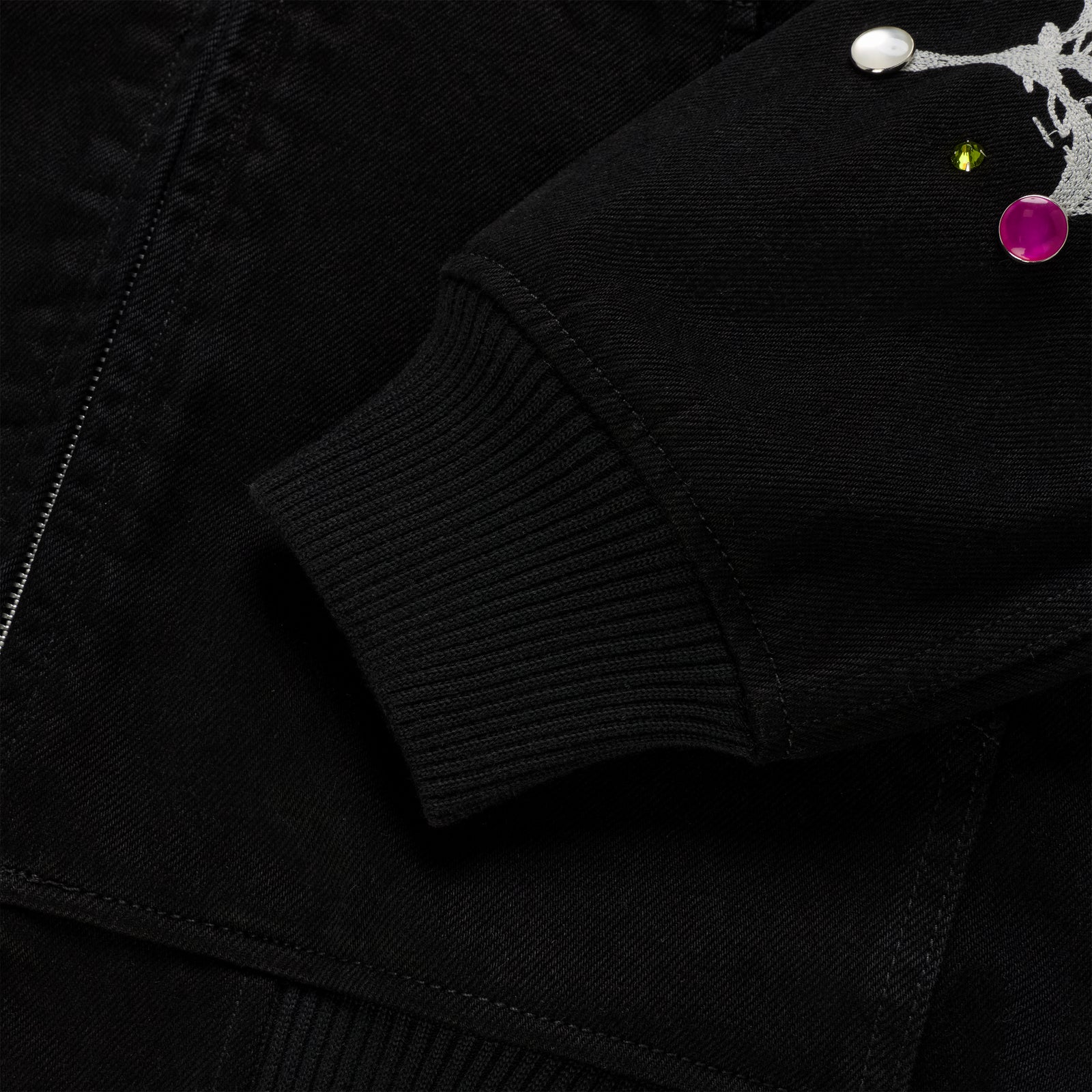 Black cotton canvas jacket sleeve with rib-knit cuff, zip closure, and colorful rhinestone embellishments.