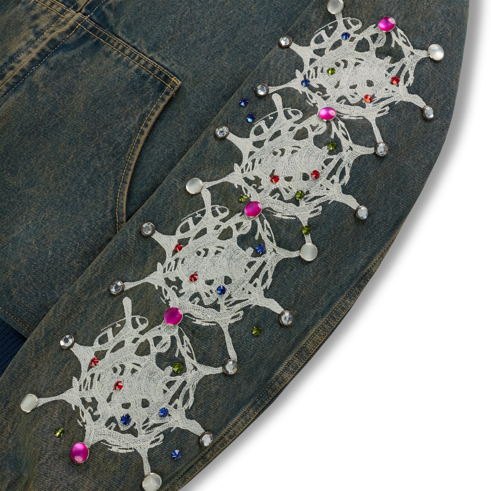 Faded denim jacket sleeve with white web print and colorful rhinestone embellishments.