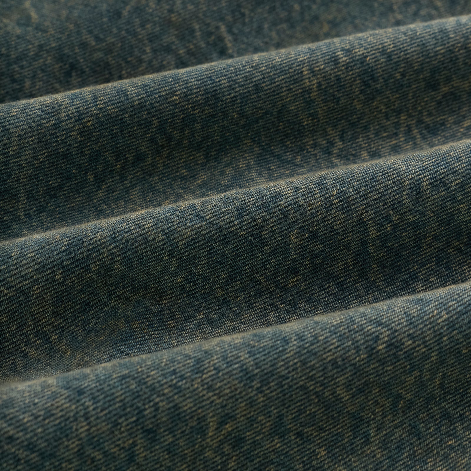 Close-up of faded blue denim fabric with subtle texture and folds.
