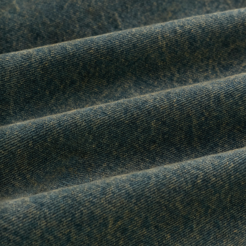 Close-up of faded blue denim fabric with subtle texture and folds.