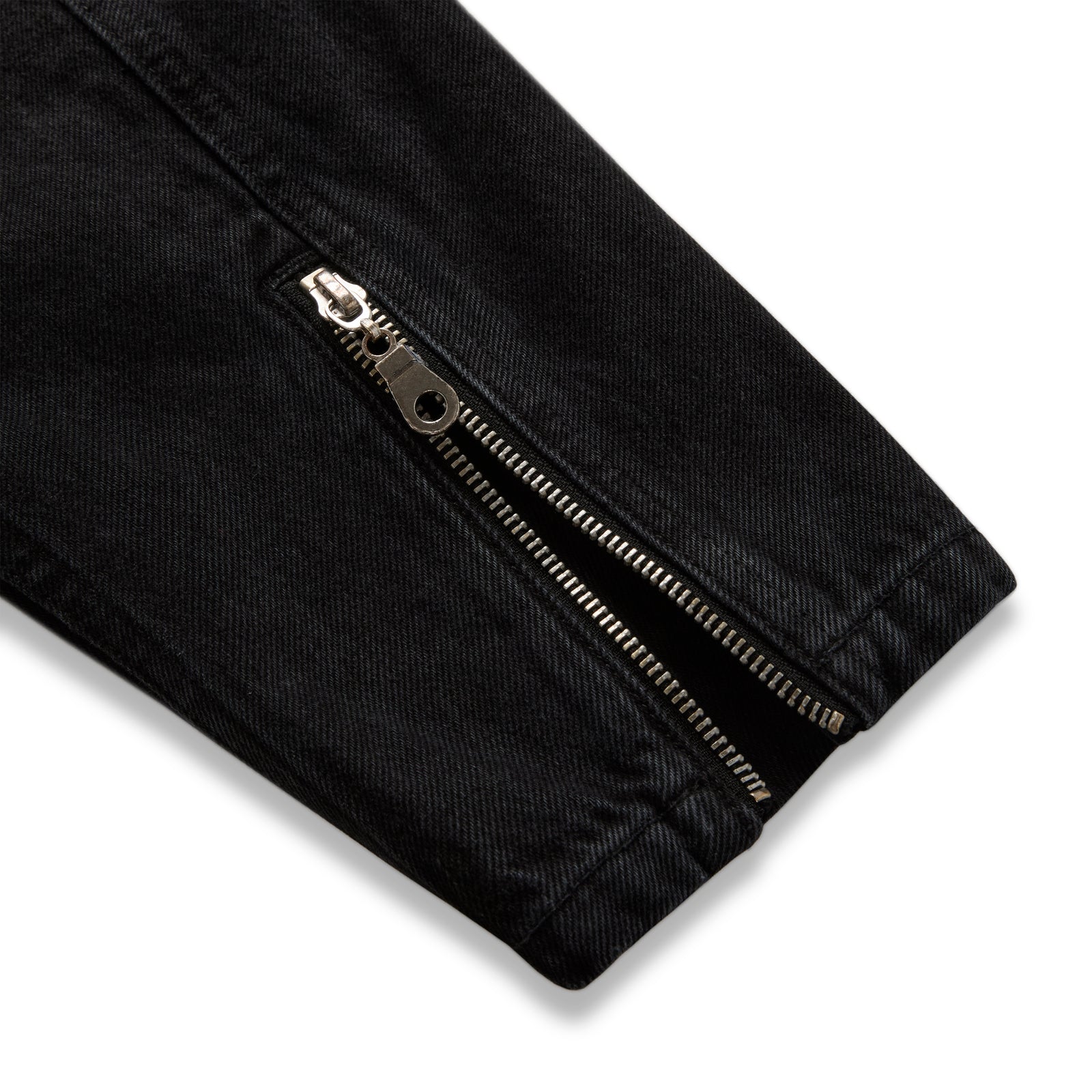Faded black denim jacket sleeve with silver zip expansion panel at cuff.