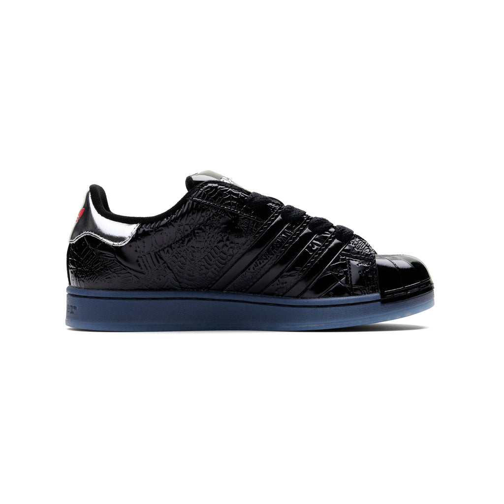 SP5DER x ADIDAS SUPERSTAR black glossy patent leather sneaker with blue midsole and spider charm.