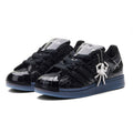 SP5DER x ADIDAS SUPERSTAR black glossy patent leather sneakers with spider charm and blue translucent sole.