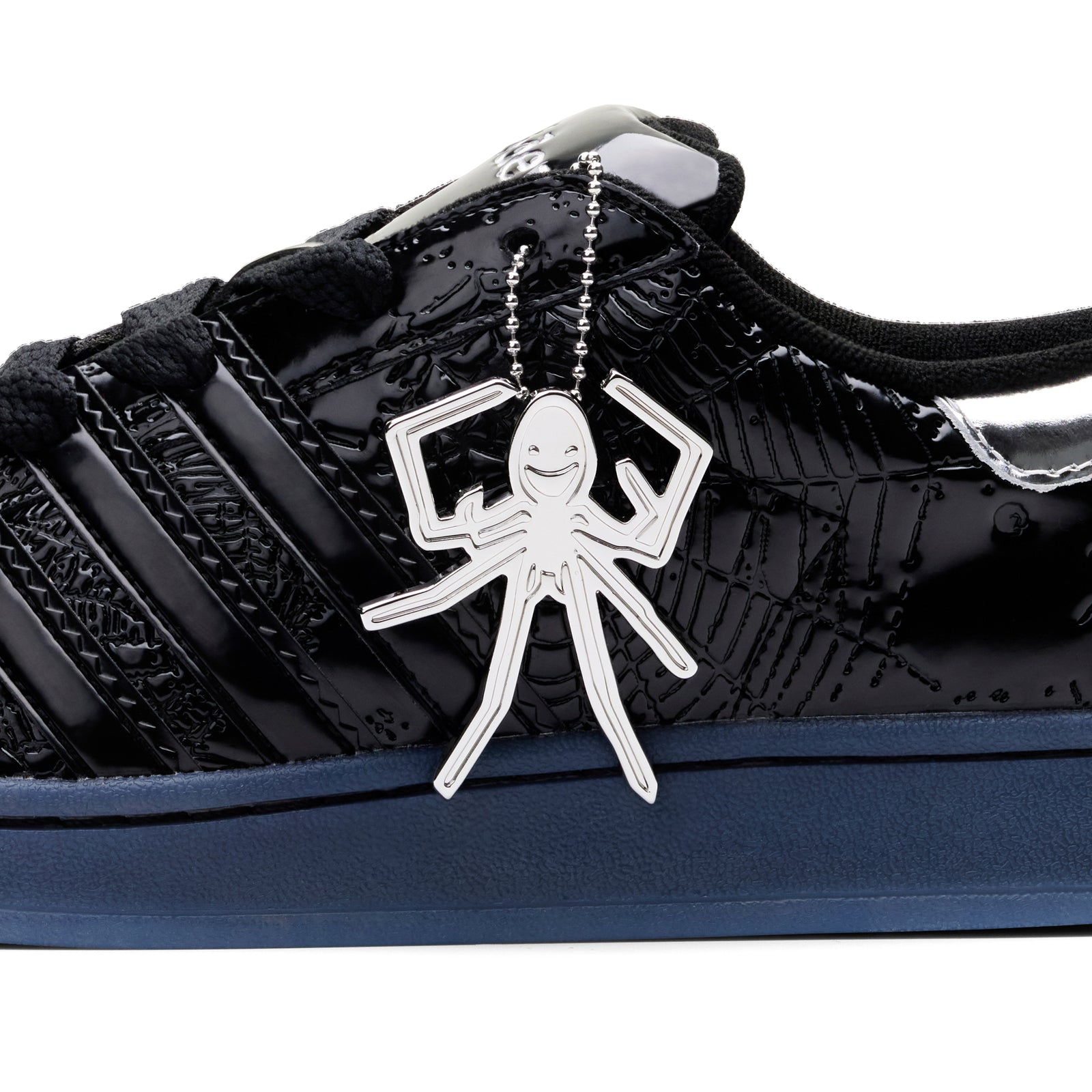 SP5DER x ADIDAS SUPERSTAR in glossy black patent leather with a silver spider charm and web detailing.