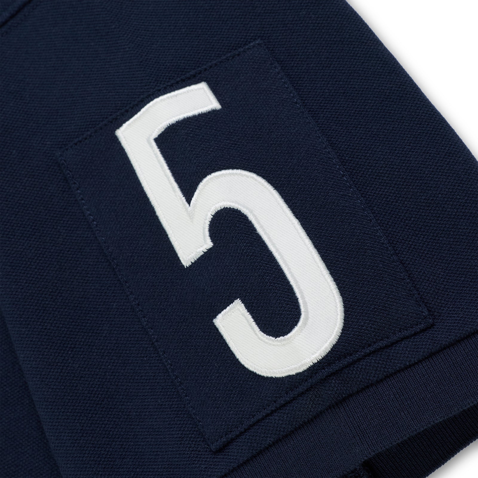 Navy blue polo shirt sleeve with a white embroidered "5" patch.