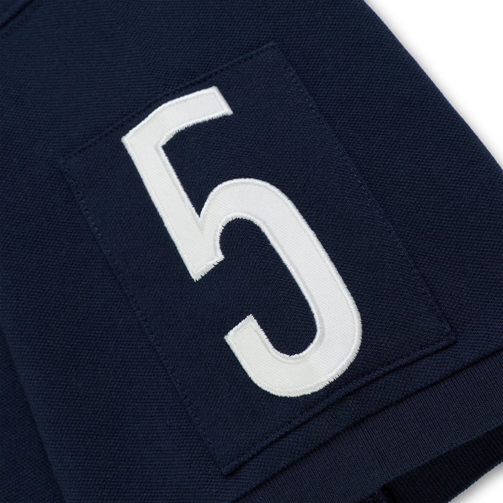 Navy blue polo shirt sleeve with a white embroidered "5" patch.