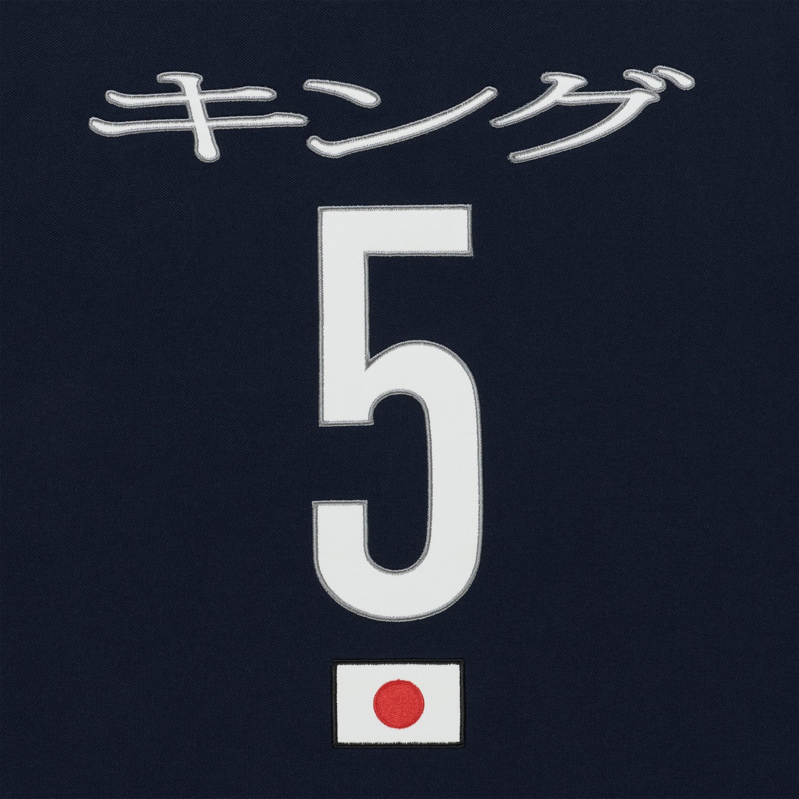 Navy polo with embroidered white Japanese text, large white number 5, and a small Japanese flag patch.
