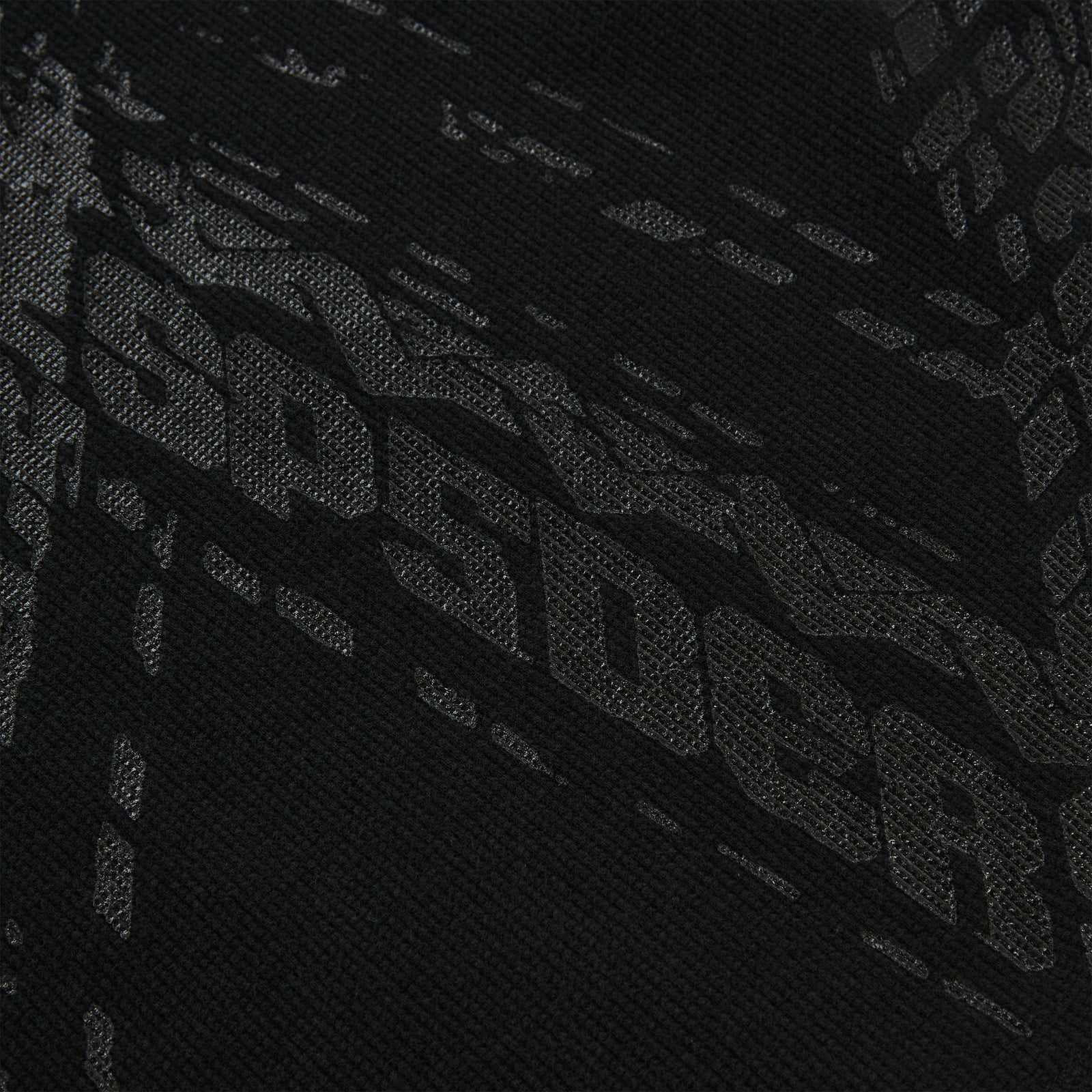 Close-up of black waffle knit thermal with subtle tire track print.