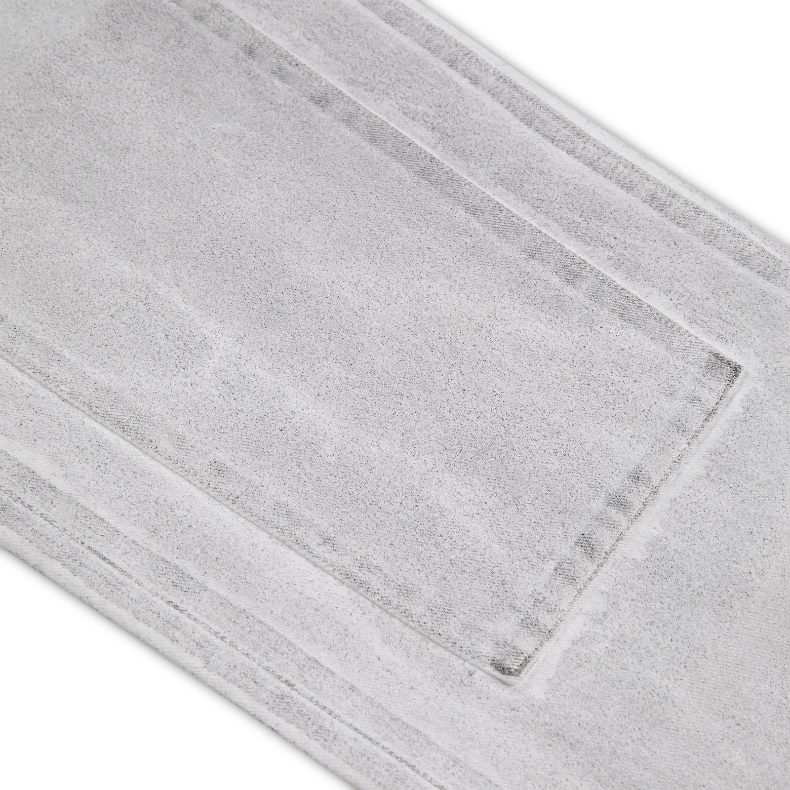 Close-up of light gray spray-effect denim pant with visible panel stitching and textured fabric.