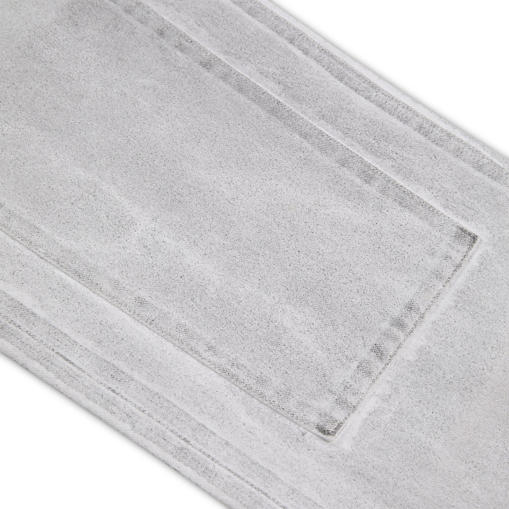 Close-up of light gray spray-effect denim pant with visible panel stitching and textured fabric.