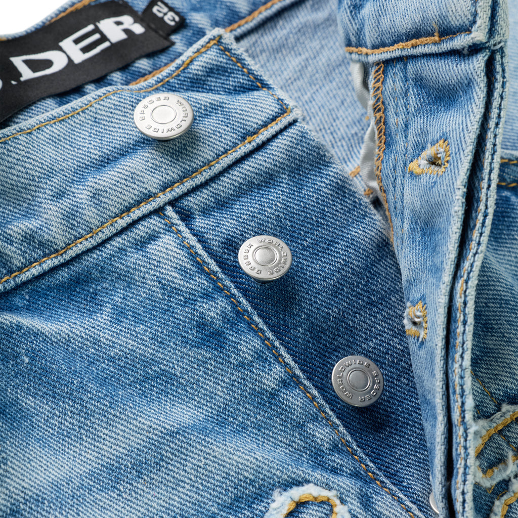 Distressed vintage wash denim jeans with branded shank buttons and frayed SP5DER logo.