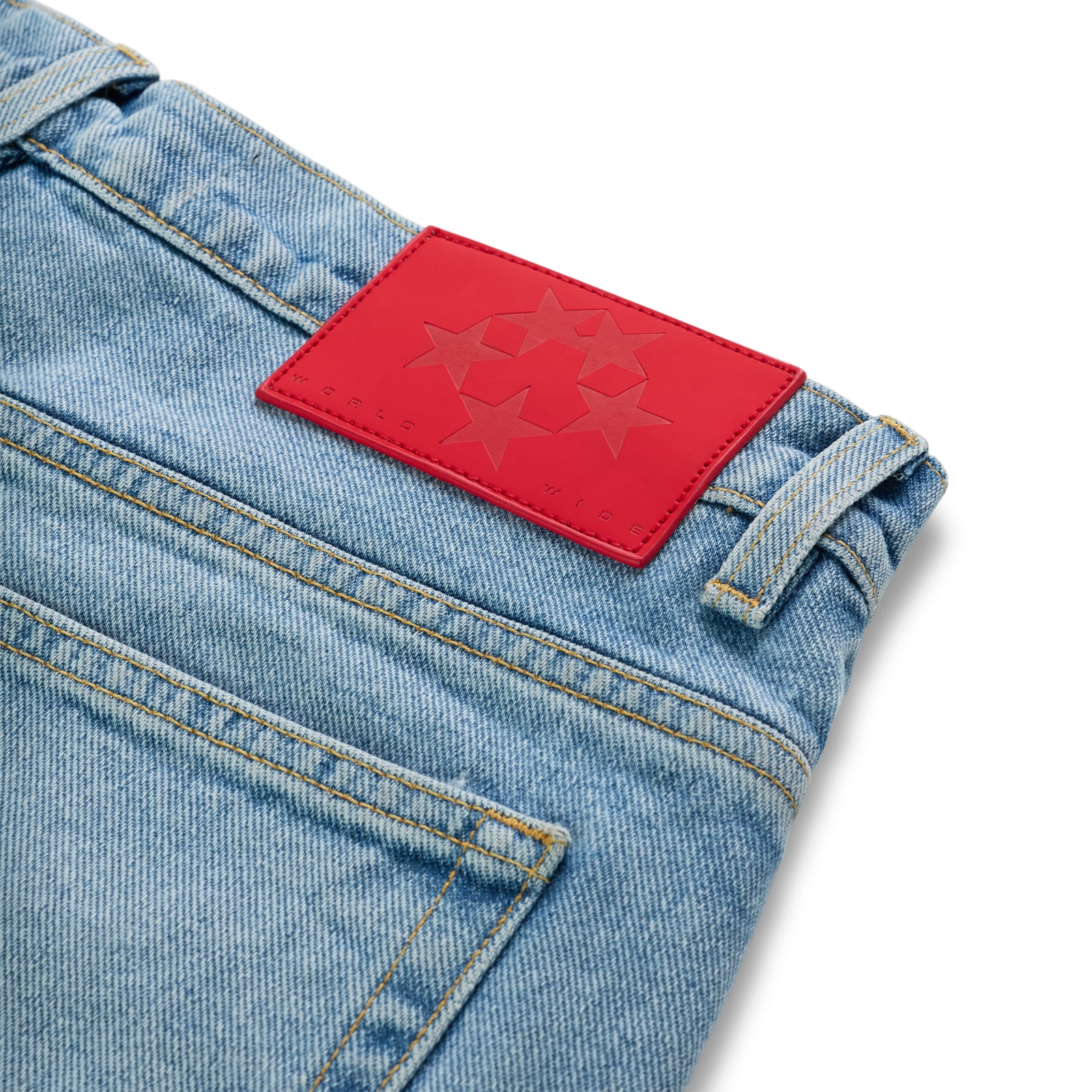 Light wash denim jeans with a red leather back patch featuring a star logo.