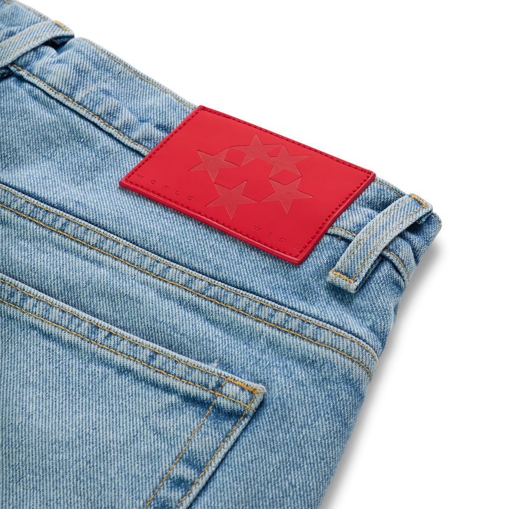 Light wash denim jeans with a red leather back patch featuring a star logo.