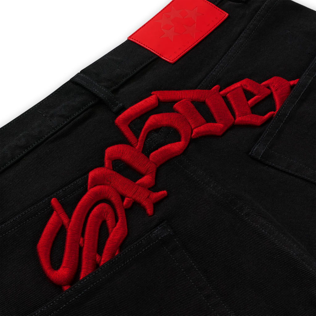 Black 13oz denim jeans with bold red embroidered text above back pockets and a red leather back patch.