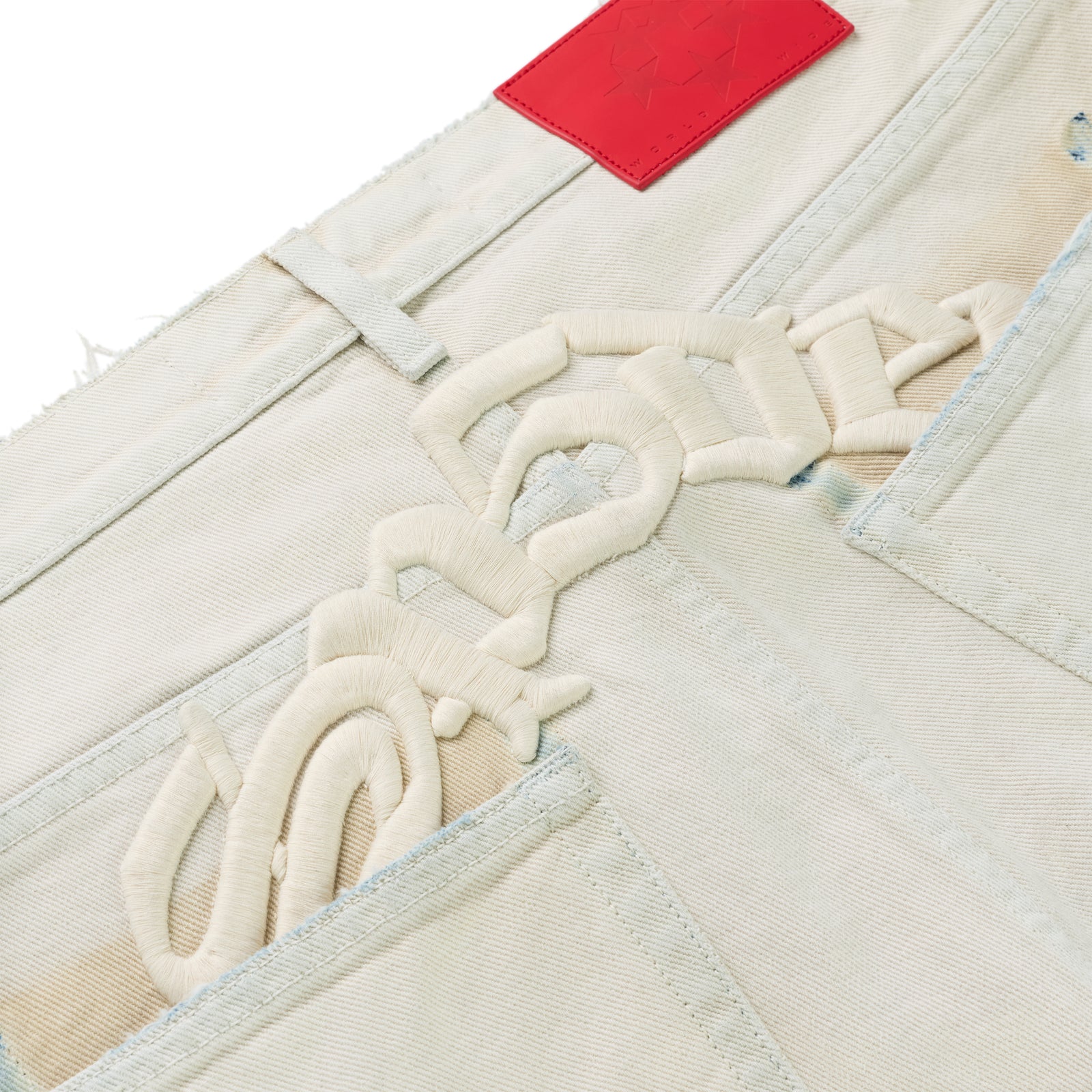Light wash OXY JEAN with cream embroidered text and red branded leather patch.