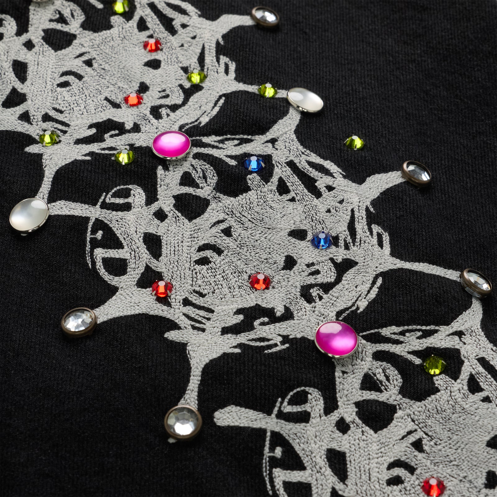 Close-up of black 13oz denim with intricate gray web print and colorful rhinestone embellishments.