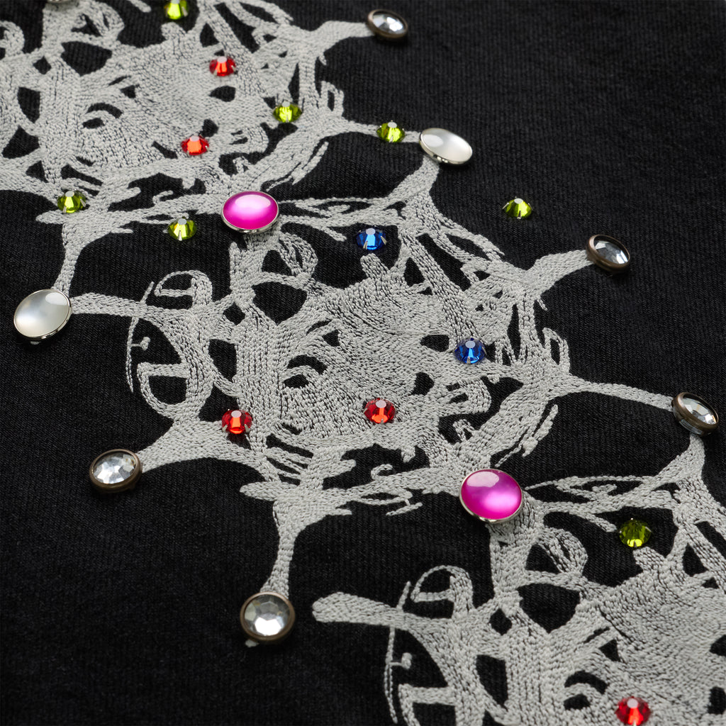 Close-up of black 13oz denim with intricate gray web print and colorful rhinestone embellishments.