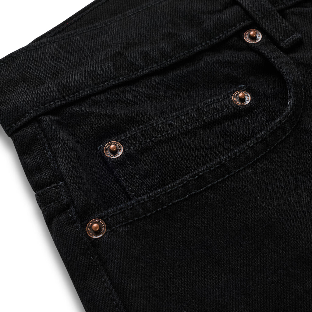 Close-up of black 13oz denim pants with custom branded copper hardware on front pockets.