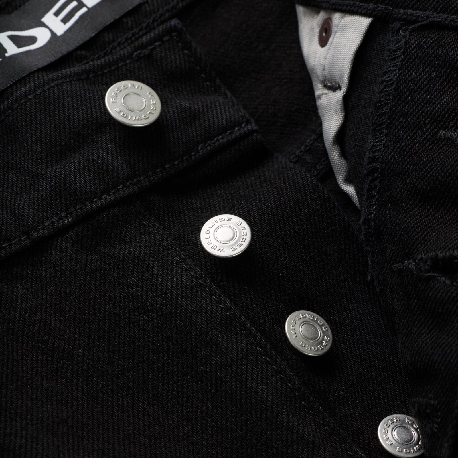Close-up of black 13oz denim pants with branded silver shank buttons on the fly.
