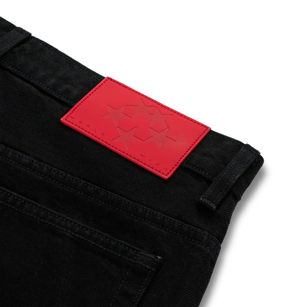 Close-up of black denim pants with a red leather back patch featuring four stars and "WORLD WIDE" text.